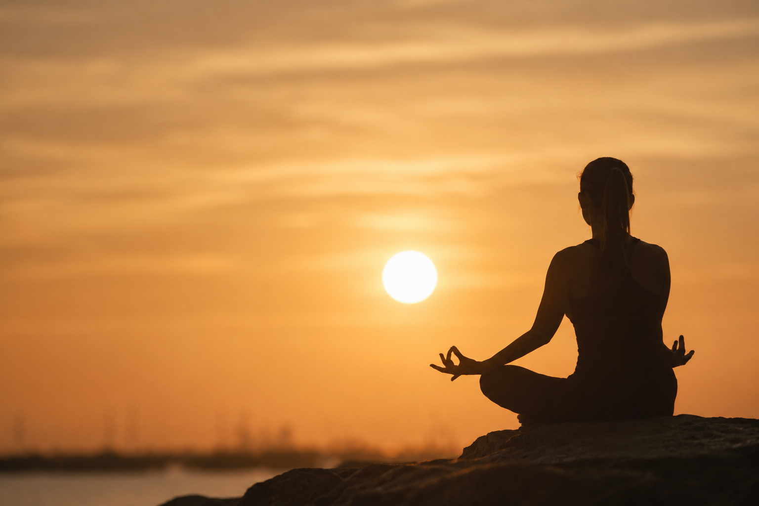 Silhouette of a woman meditating at sunset